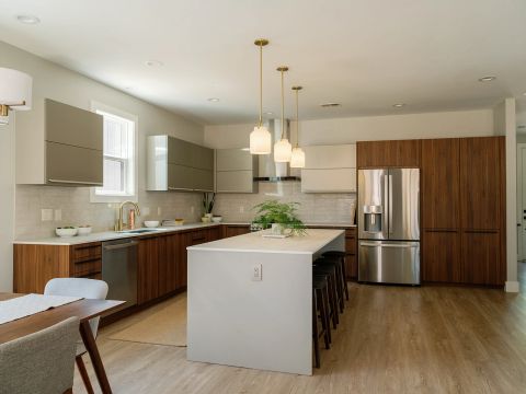 Greenville kitchen with white waterfall island, walnut lower cabinets, taupe and white upper cabinets, gold pendant lights, and stainless steel French-door refrigerator by Tekton Builds.