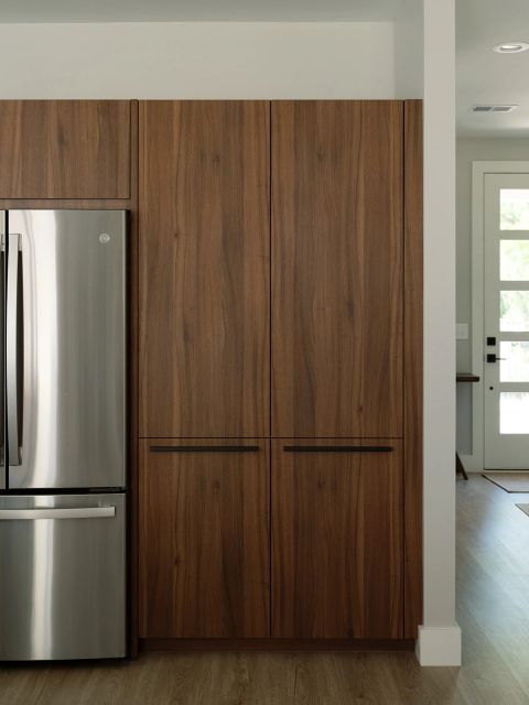 Greenville kitchen with floor-to-ceiling walnut pantry cabinetry, black horizontal pulls, and stainless steel GE refrigerator by Tekton Builds.