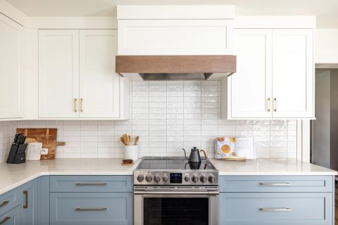 Taylors kitchen with two-tone shaker cabinetry, white quartz countertops, subway tile backsplash, stainless steel slide-in range, and wood-accented range hood by Tekton Builds.